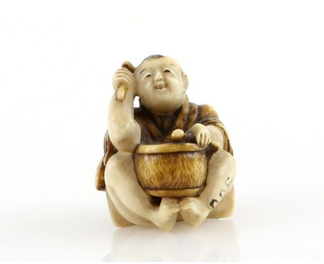 A small stained ivory netsuke of a boy beating a drum, the himotoshi beneath his feet, 19th or 20th CenturyProvenance: The Pr