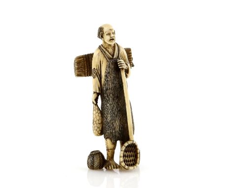 A heavily stained ivory okimono carved as a standing farmer, holding a net with his left hand and carrying a bundle on his ba
