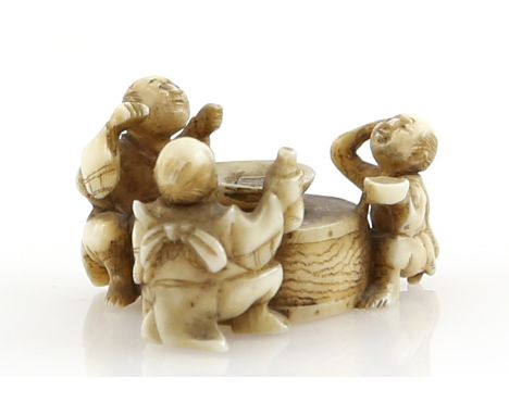 A small stained ivory netsuke of three sake tasters, seated beside a large sakazuki, 19th or 20th CenturyProvenance: The Prop