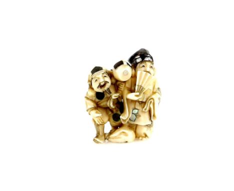 An ivory netsuke carved as Daikoku  with his lucky mallet beside Hotei, or another figure, hiding behind a fan, 19th or 20th 