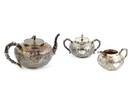 Early 20th century Chinese silver three piece tea service, comprising teapot, cream jug and sugar bowl and cover, embossed wi