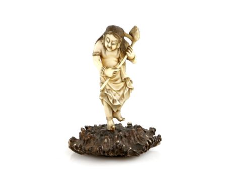 A small stained ivory okimono carved as a Sennin, or other similar character, holding a lotus flower with both hands whilst s