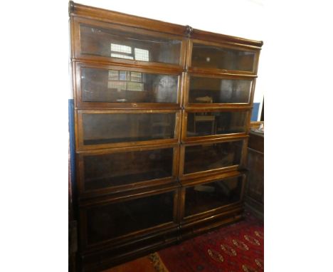 A pair of Globe Wernicke oak five tier stacking bookcases with folding glazed fronts and base drawers, 76" x 34" each