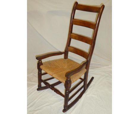 A 19th Century beech and elm ladder back country-style rocking chair with rush work seat on turned supports