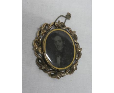 A Victorian pinchbeck oval mourning brooch with inset male bust portrait, the reverse with plaited hair display