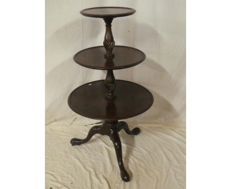 A George III and later mahogany circular three tier dumb waiter with turned columns and tripod base