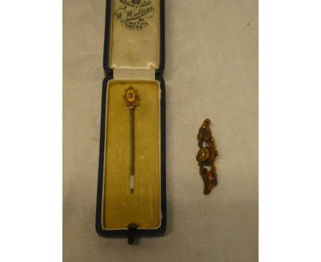 A 15ct gold stick pin set a small diamond and a 15ct gold bar brooch with scroll decoration set a diamond (2)