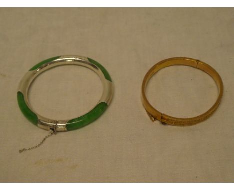 A 9ct gold oval bangle with engraved decoration and one other jade mounted circular bangle (2)