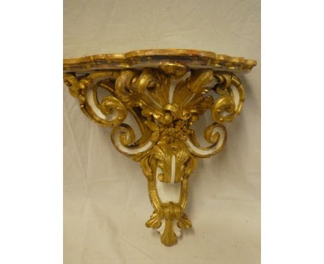 An ornate painted wood and plaster wall bracket with raised scroll decoration, 18" long