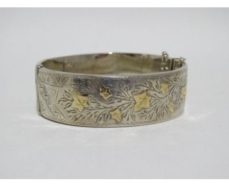 A silver bangle - with foliate engraving incorporating gilt leaves, Birmingham 1949, sponsor's mark for Smith &amp; Pepper Lt