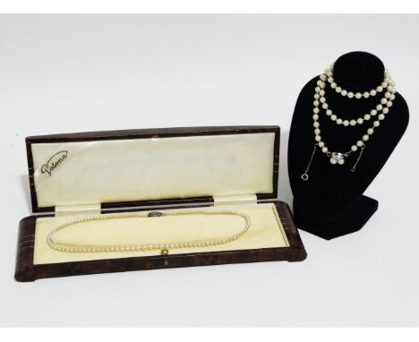 A uniform string of pearls - with silver clasp, length 58cm, together with another graduated string of pearls, in a Art Deco 