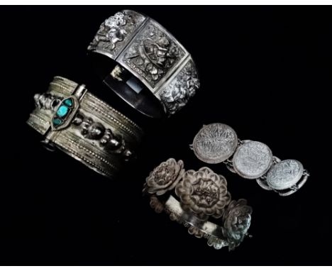 An Indian silver bangle - Constructed of hinged tapering panels depicting deity, together with a floral filigree bangle and t