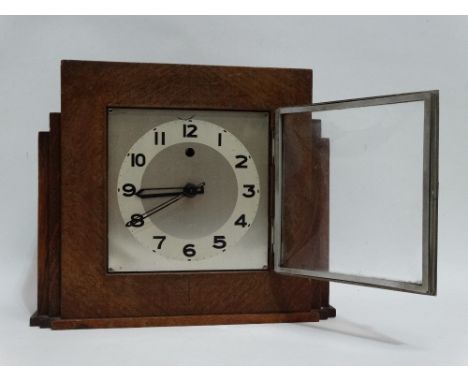 An oak cased Art Deco style mantel clock - the silvered square dial set out with Arabic numerals fitted with an electric move