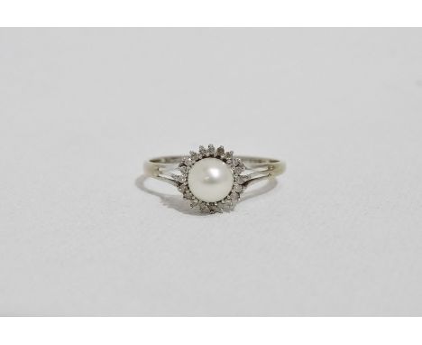 A pearl and diamond dress ring - the central pearl within a band of claw set diamonds, set on a 9ct. white gold band, size W,