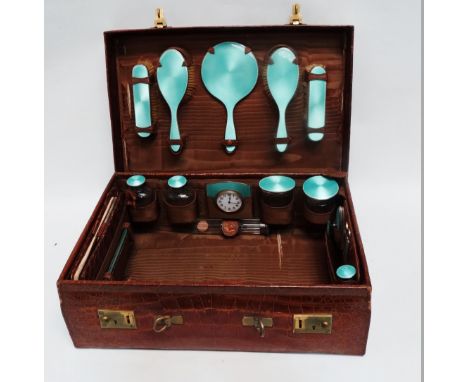 An early 20th century tan crocodile skin travelling dressing case - fully fitted, the silver items finished with a turquoise 