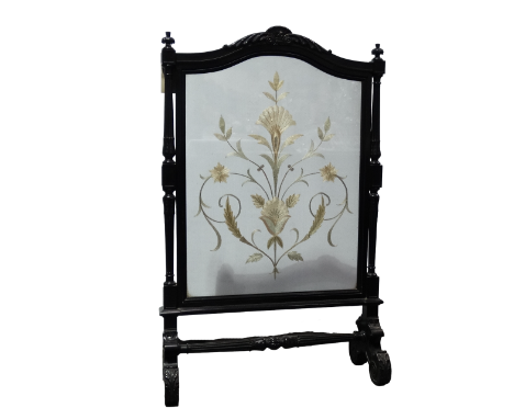 A Victorian ebonised fire screen - the frame with an arched rail flanked by square and fluted columns, enclosing an embroider