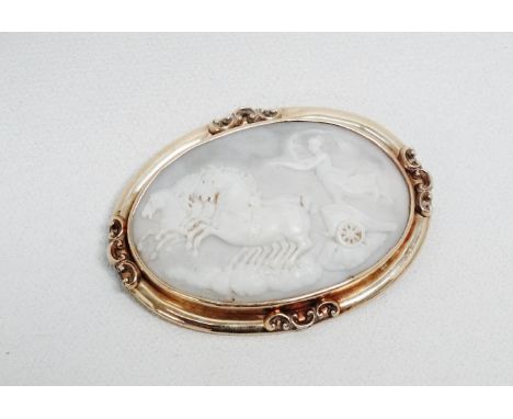 A late 19th century oval cameo brooch - the panel showing a charioteer within a yellow metal mount, length 7cm.