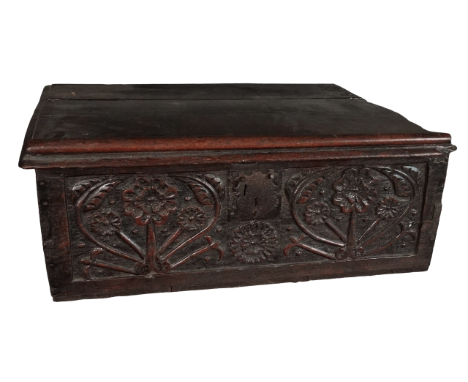 A 17th century oak bible box with later restoration - the hinged top enclosing a void interior above a foliate carved panel, 