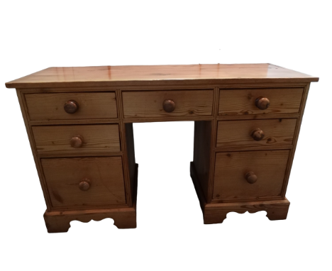 A 20th century pine kneehole desk - the rectangular top above an arrangement of seven drawers with bun handles, on shaped bra