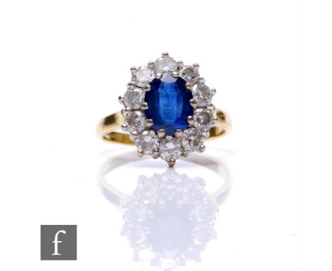An 18ct hallmarked sapphire and diamond cluster ring, central oval sapphire, length 9mm, within a border of ten brilliant cut