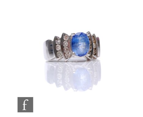 A 14ct white gold tanzanite and diamond ring, central oval tanzanite, length 8mm, flanked by two rows of channel set diamonds