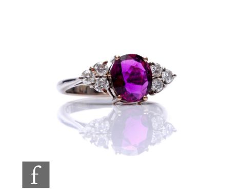 An 18ct hallmarked white gold ruby and diamond ring, central oval ruby, length 8mm, flanked by three diamonds to each shoulde