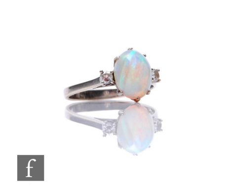 An 18ct hallmarked white gold opal and diamond three stone ring, central oval opal, length 10mm, flanked with a diamond to ea