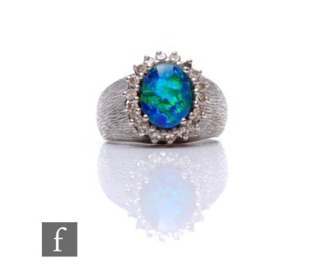 An 18ct hallmarked white gold opal doublet and diamond cluster ring, central opal within a border of seventeen diamonds (one 