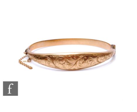 A 9ct hallmarked hinged bangle with foliate engraved decoration to front, weight 8.7g, Chester 1961, slight damage. 