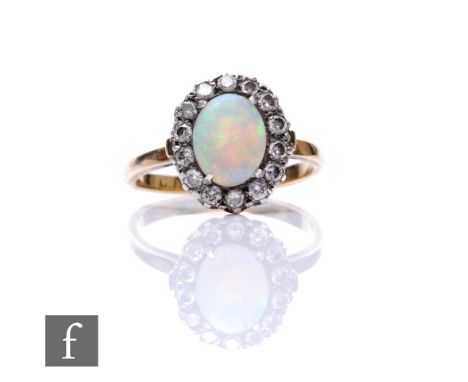 An early 20th Century 18ct opal and diamond cluster ring, central oval opal, length 9mm, within a border of fourteen diamonds