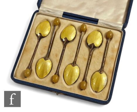 A cased set of six hallmarked silver coffee bean spoons each with yellow enamel decoration to bowl reverse, Birmingham 1932. 