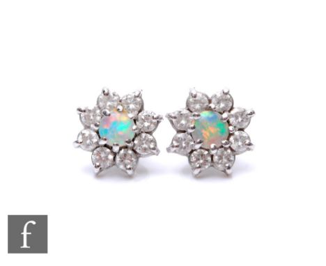 A pair of 9ct white gold opal and diamond cluster stud earrings, central opal within a border of eight brilliant cut diamonds