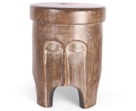 An African Tribal carved wood trunk stool, with stylised facial body, diameter 28cm, height 36cm 