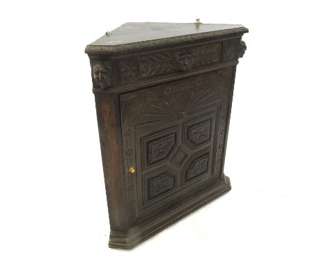 A heavily carved oak corner cupboard, opening to reveal a shelf with lion mask, width 24ins Condition report: Brass handle  n