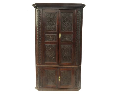 A large 19th century oak free standing corner cupboard, with carved panel doors, opening to reveal shaped shelves, height 91i