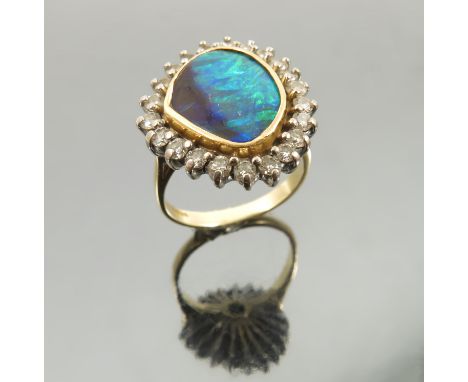 A boulder opal and diamond cluster 18 carat gold ring, the asymmetrical flat stone enclosed by twenty two brilliant cuts tota