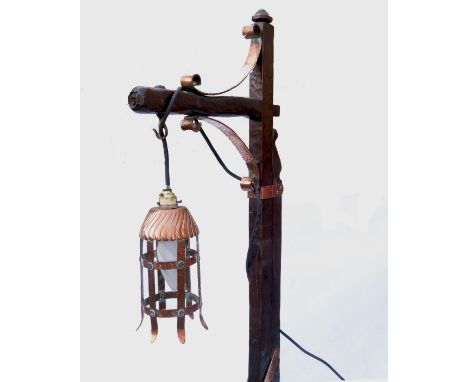 An Arts & Crafts style oak standard lamp with adjustable column, with copper mounts and bracket supporting a pierced brass la