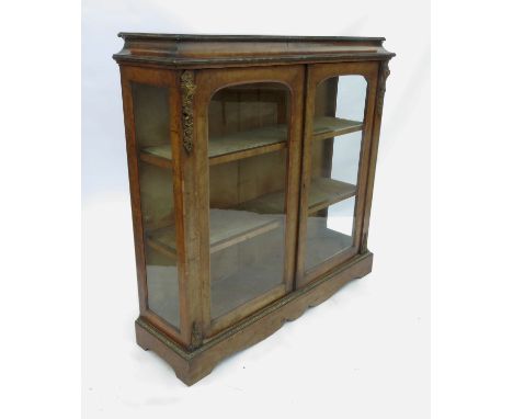 A Victorian burr walnut double door pier cabinet, having a crossbanded top, cushion frieze, two arch glazed doors opening to 