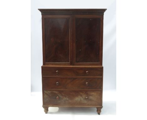 A 19th century mahogany press cupboard, having two panel doors opening to reveal five slide out drawers, having three long dr