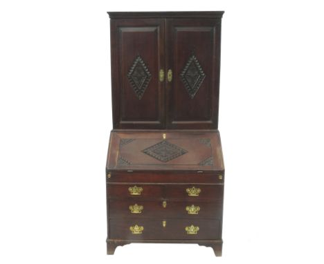 A late Georgian oak bureau bookcase, having blind panel doors to the upper section, a stepped interior with pigeonholes and d