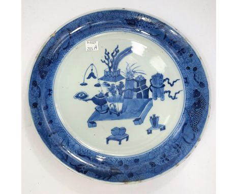 A Chinese blue and white ceramic plate with vases and a writing desk and equipment with a border featuring fish, carp etc, wi