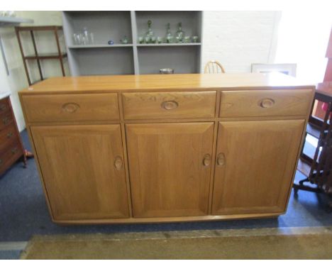 An Ercol light oak Windsor sideboard with three drawers above three cupboard doors on plinth base 36 1/2" x 61" x 17", with E