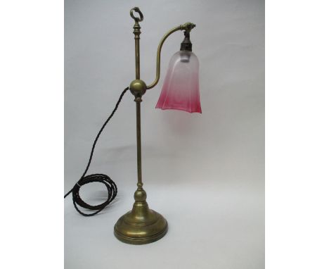 An early 20th century brass height adjustable lamp with a ring handle, S shaped branch and clear and cranberry glass shade, o