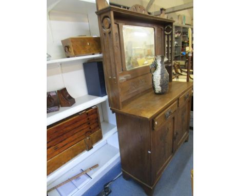 An Art Nouveau oak dresser, the top with pierced pediment over a shelf and central bevelled mirror, flanked by carved styaliz