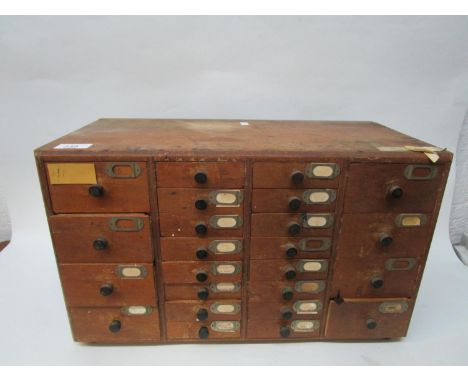 Industrial design - a small early to mid 20th century wooden tool cabinet, two rows of eight small central drawers, flanked b