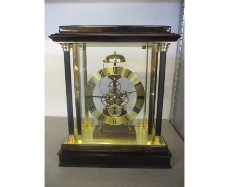 A modern skeleton clock having four glass panels flanked by columns, striking on a bell 