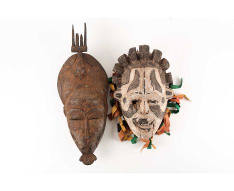 A Senufo Kpelie mask, Ivory Coast, the tall headdress surmounted by an inverted fork with figural terminal, scarifications to