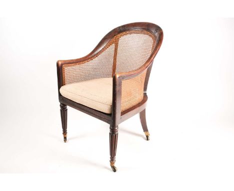 An early 19th century simulated rosewood hoop backed Bergere library chair with split can panel seat and back. On cluster col