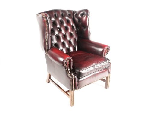 A George III style deep button "Ox Blood" hide upholstered hipped wing back fireside chair. With close nailed detail. Support