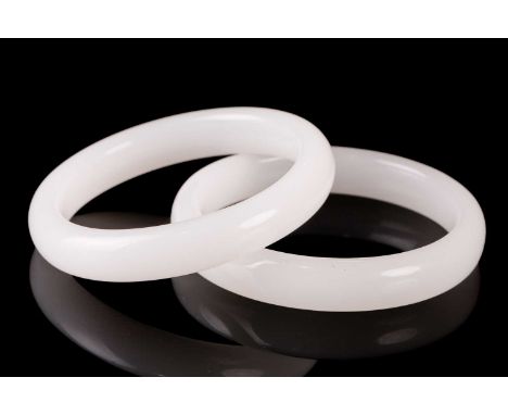 A pair of matching of white carved jade bangles of plain form. 8 cm diameter the slightly largestCondition report: No apparen